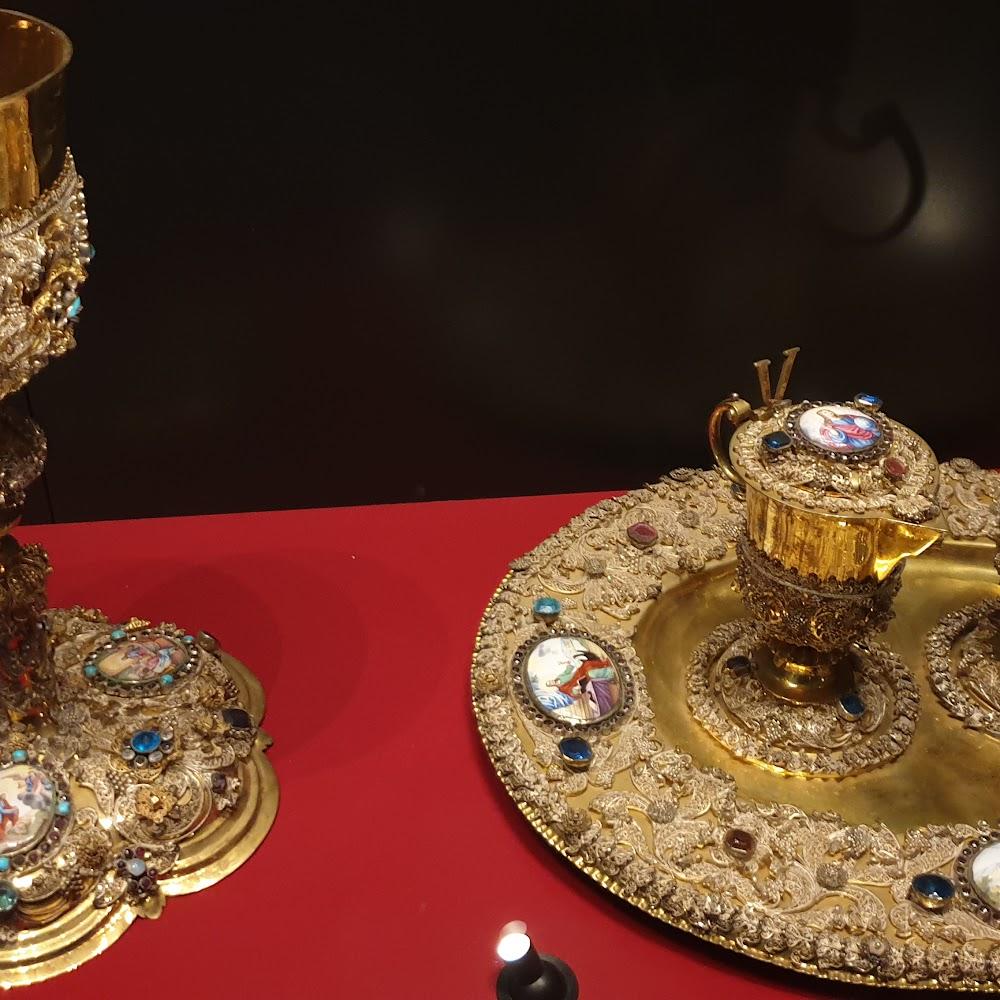 Gold chalice, paten and pitcher on red velvet.
